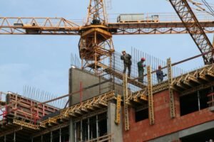 casa in costruzione con gru e operai