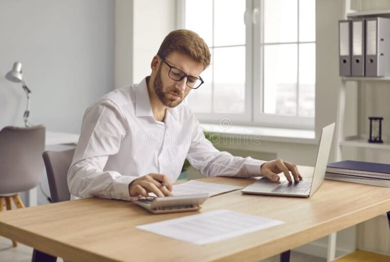 imprenditore al lavoro con calcolatrice e laptop
