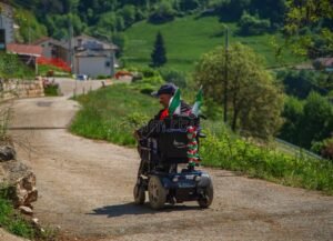 persona con sedia a rotelle e bandiera italiana